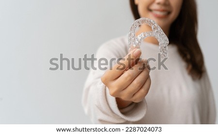 close up woman hand holding dental aligner retainer (invisible) on background for beautiful teeth and dental treatment course concept Royalty-Free Stock Photo #2287024073
