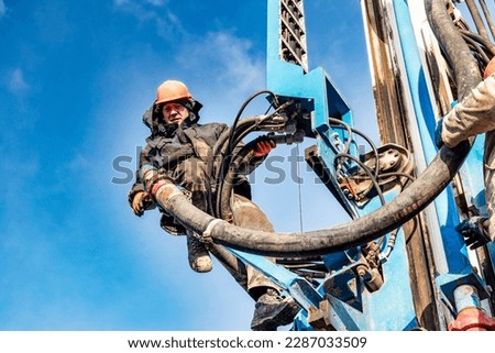 Worker on the mast of the drilling rig close-up. Drilling of deep wells. Mineral exploration. Extraction of gas and oil. Drilling operations in difficult conditions Royalty-Free Stock Photo #2287033509