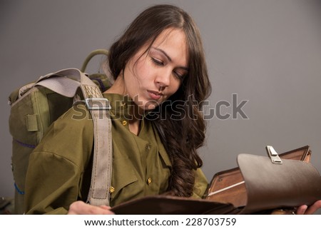 girl in the uniform of the Soviet army and parachute watching pensive at leather bag board