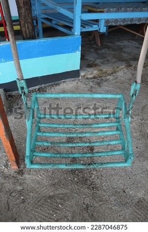swing made of iron painted in green color which is located on the brown sand beach. Royalty-Free Stock Photo #2287046875
