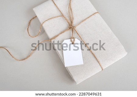 Empty price tag on white fabric, label mockup, folded fabric with tag on white background