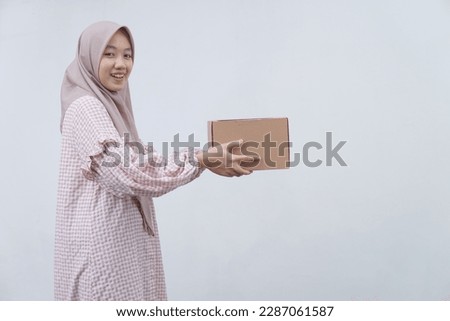 Beautiful moslem girl carrying a package or brown cardboard box 
