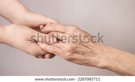 The hand of a young girl reaches for an old hand. Help for the elderly. Royalty-Free Stock Photo #2287085711