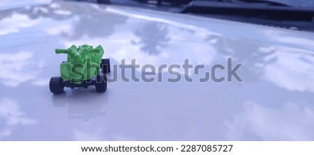a green toy ATV on the hood of the car 1