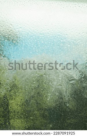 Raindrops on glass during rain, large drops. Landscape with raindrops falling on the window of the house. Blurred horizon view. macro photo