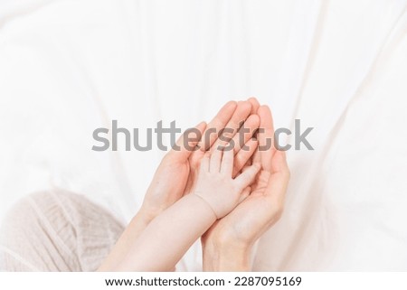 There are mother’s palms on the background of a white cloth and the asian korean newborn baby has her hands on it. There is a large empty blank space to use as a copyspace. Royalty-Free Stock Photo #2287095169