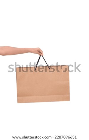Paper shopping bag. The woman holds it with her hand. Delivery service concept. Shopping concept. For gift giving. Isolated on white background