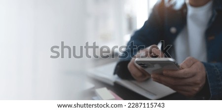 Business woman hand using mobile phone, typing on smartphone screen during planning work with calendar planner and laptop computer on office table, close up
