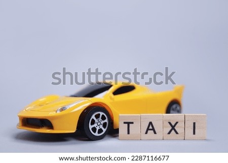Toy car and word taxi made of wooden letters, cab passenger transportation concept
