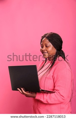 Young adult navigating on social media and online website network using laptop computer over isolated background. Cheerful african american model browsing webpages on internet on gadget