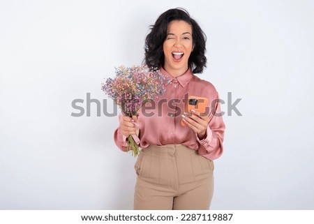 beautiful woman holding a bouquet of flowers over white background taking a selfie celebrating success