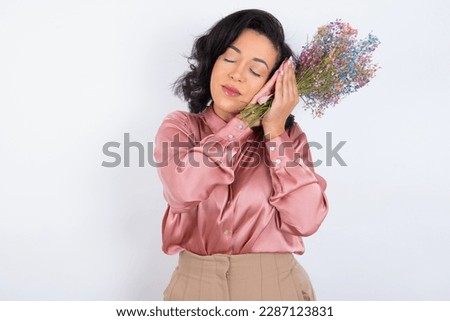 beautiful woman wearing pink shirt over white background sleeping tired dreaming and posing with hands together while smiling with closed eyes.