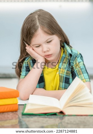Bored little girl reads the book at home