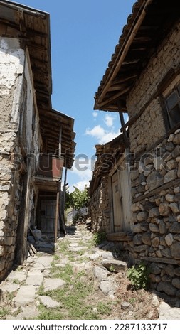 The photo was taken in a high mountain almost deserted village in Bulgaria. On it, you can see the narrow stone road and tall two-story houses, built from stone and adobe.