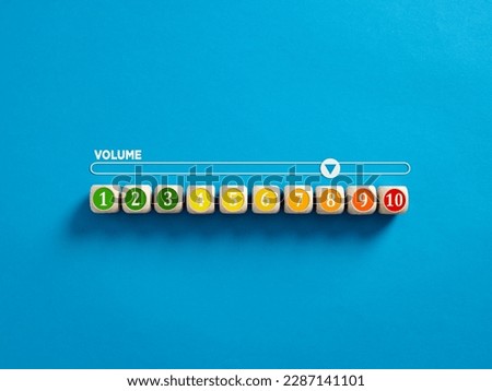 Indicator measuring volume level. High level of sound volume. Volume level numbers on wooden cubes with a volume meter on blue background. Royalty-Free Stock Photo #2287141101