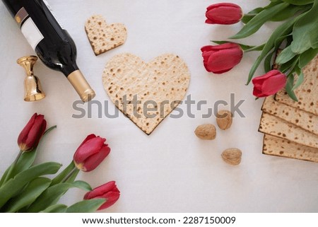 Matzah shape of heart with red tulips and wind kosher on white background. Traditional of  Holiday on Passover. Home symbol of lovely Jewish family in pesach. top view