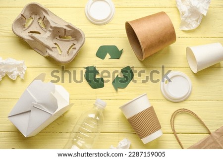 Recycling sign with garbage on yellow wooden background