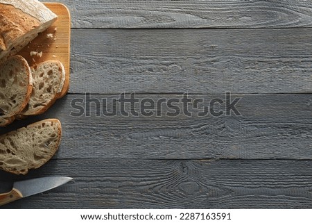Food photography. Cut freshly baked bread and knife on wooden table, flat lay with space for text