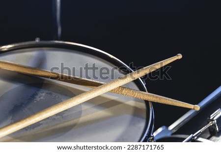Close-up, snare drum and drumsticks on a dark background.