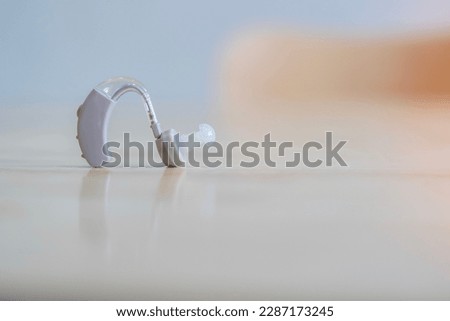 Close up of hearing aid for the treatment of deafness and hearing loss in humans. Hearing aid on the light wooden table and selective focus. Royalty-Free Stock Photo #2287173245
