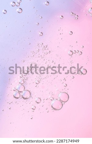 Facial serum oil surface with water bubbles. Abstract cosmetic liquid pink background for advertising and presentation of cosmetic products. Macro photo, vertical