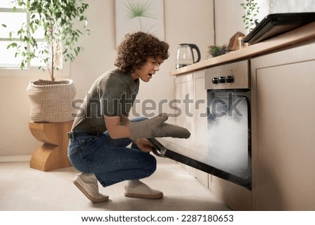 Housewife opening the oven door and taking out burnt food during her cooking in the kitchen Royalty-Free Stock Photo #2287180653