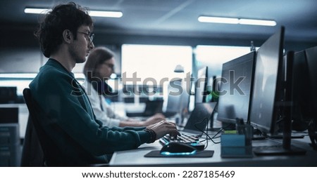 Portrait of a Thoughtful Engineer Working on Desktop Computer in a Technological Office Environment. Research and Development Department Writing Software Code for an Innovative Internet Project Royalty-Free Stock Photo #2287185469