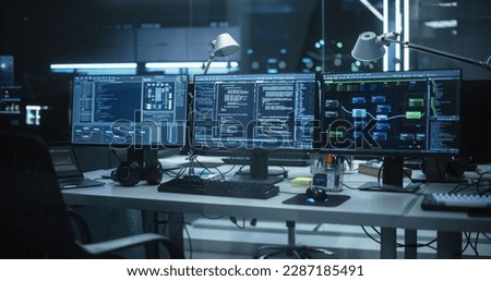 Empty Software Developer Office Workplace with a Desk with Multiple Computer Screen with Programming Code, Big Data Models, Back-End of Artificial Intelligence and Neural Network Technology Systems Royalty-Free Stock Photo #2287185491