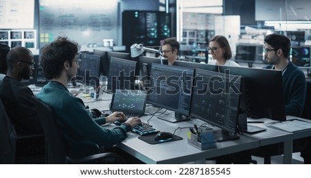 Group of Empowered Multicultural Men and Women Working in a Research Center, Using Computers to Run Advanced Software, Develop Artificial Intelligence Interface and Cyber Security Protocols Royalty-Free Stock Photo #2287185545