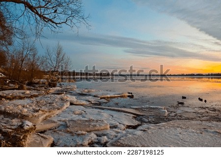 sunset, in the photo the evening sky and the river in winter in the foreground ice floes.