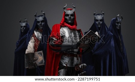 Portrait of dark cult members dressed in robes and their leader holding book. Royalty-Free Stock Photo #2287199751