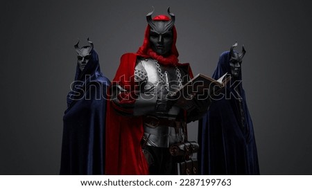 Portrait of two members of mysterious cult and their chief with book. Royalty-Free Stock Photo #2287199763
