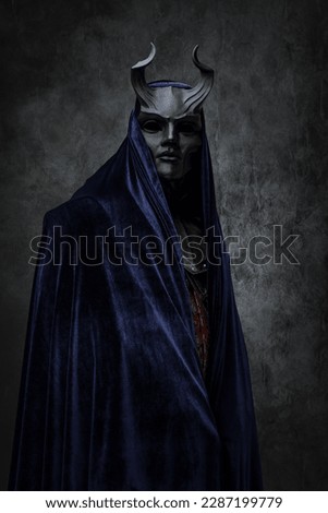Shot of ancient cult prayer dressed in horned mask and dark robe. Royalty-Free Stock Photo #2287199779