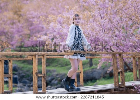 Teenage girl happy in the fresh beautiful Wild Himalayan, Cherry pink blossom Sakura flowers full bloom in the park with a joyful holiday vacation. Concept portrait young girl fashion loves nature.