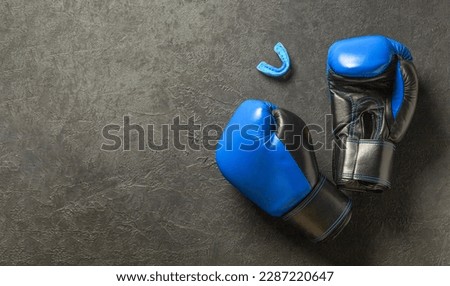 Boxing gloves of blue color with a mouthguard on a black background. Free space for text. Royalty-Free Stock Photo #2287220647