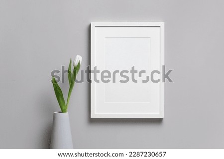 Blank vertical frame mockup with fresh tulip flower in vase, white mock up with copy space