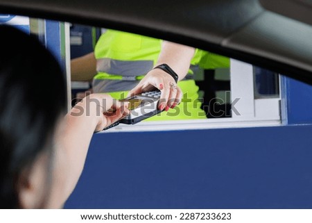 Unrecognizable woman paying with a bank card at a POS of an operator, also unrecognizable, of a toll road Royalty-Free Stock Photo #2287233623
