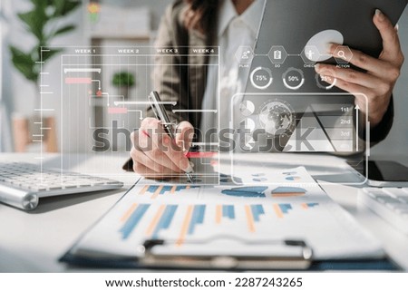Business woman hand Project manager working and update tasks and Gantt chart scheduling virtual diagram.with smart phone, tablet and laptop in office.
