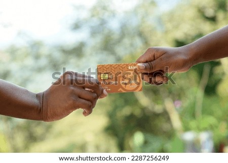 African American female hands exchanging a bank credit card. Detailed photo of a woman passing a payment credit card to the saleswoman.