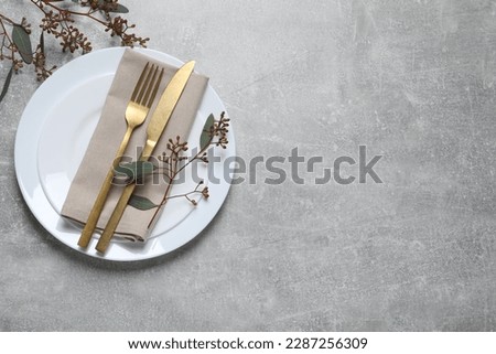 Stylish table setting with cutlery and eucalyptus leaves, top view. Space for text Royalty-Free Stock Photo #2287256309