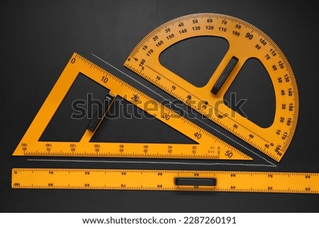 Triangle, protractor, ruler and drawn acute angle on black table, flat lay