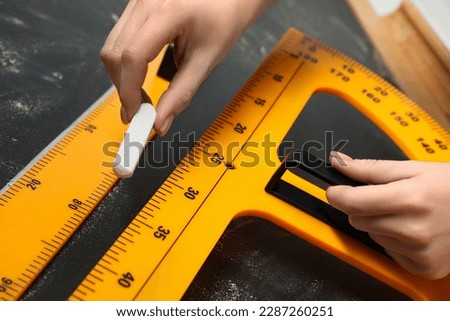 Woman drawing with chalk, ruler and protractor on blackboard, closeup