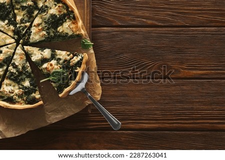 Delicious homemade spinach quiche on wooden table, top view. Space for text