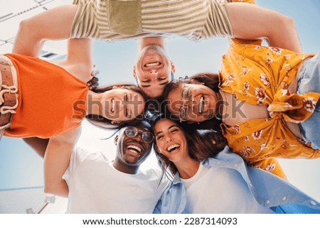 low view angle of a group of multiracial teenagers smiling and looking at camera together. Portrait of five young students smiling and laughing. Cheerful people having fun and embracing each others Royalty-Free Stock Photo #2287314093