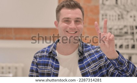 Portrait of Young Casual Man Showing Victory Sign