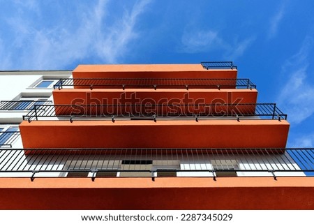 a series of red textured stucco balconies in strong perspective view. residential building elevation. steel picket rail. exterior wall. modern architecture. apartment building. diminishing perspective Royalty-Free Stock Photo #2287345029