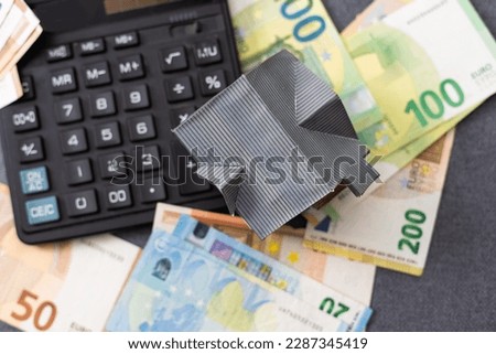 Layout of a house, banknotes , calculator lying on the table. Insurance, credit, mortgage, real estate purchase . Payment of interest on the mortgage.