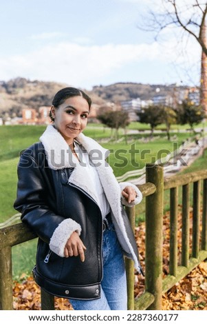 In this stunning vertical portrait photo, a beautiful Caucasian girl poses in a casual dress at a city view park, with the stunning light of the sunset illuminating the background. 