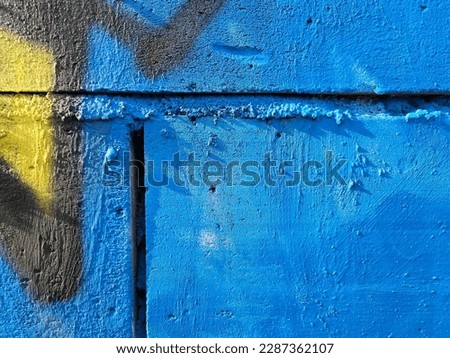 Fragment of an old wall painted with blue paint and spray paint, Lodz, Poland.