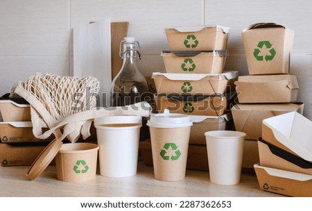 Recycling concept. Disposable tableware and packaging made from biodegradable materials with a green recycling symbol Royalty-Free Stock Photo #2287362653